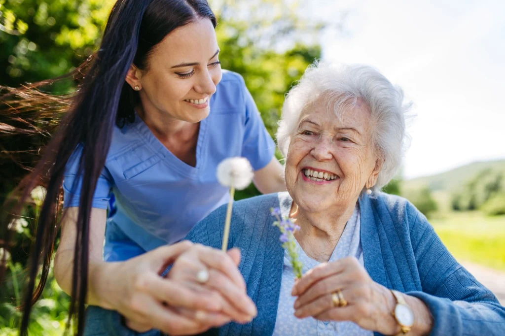 A smiling caregiver enjoying time outdoors with a senior woman