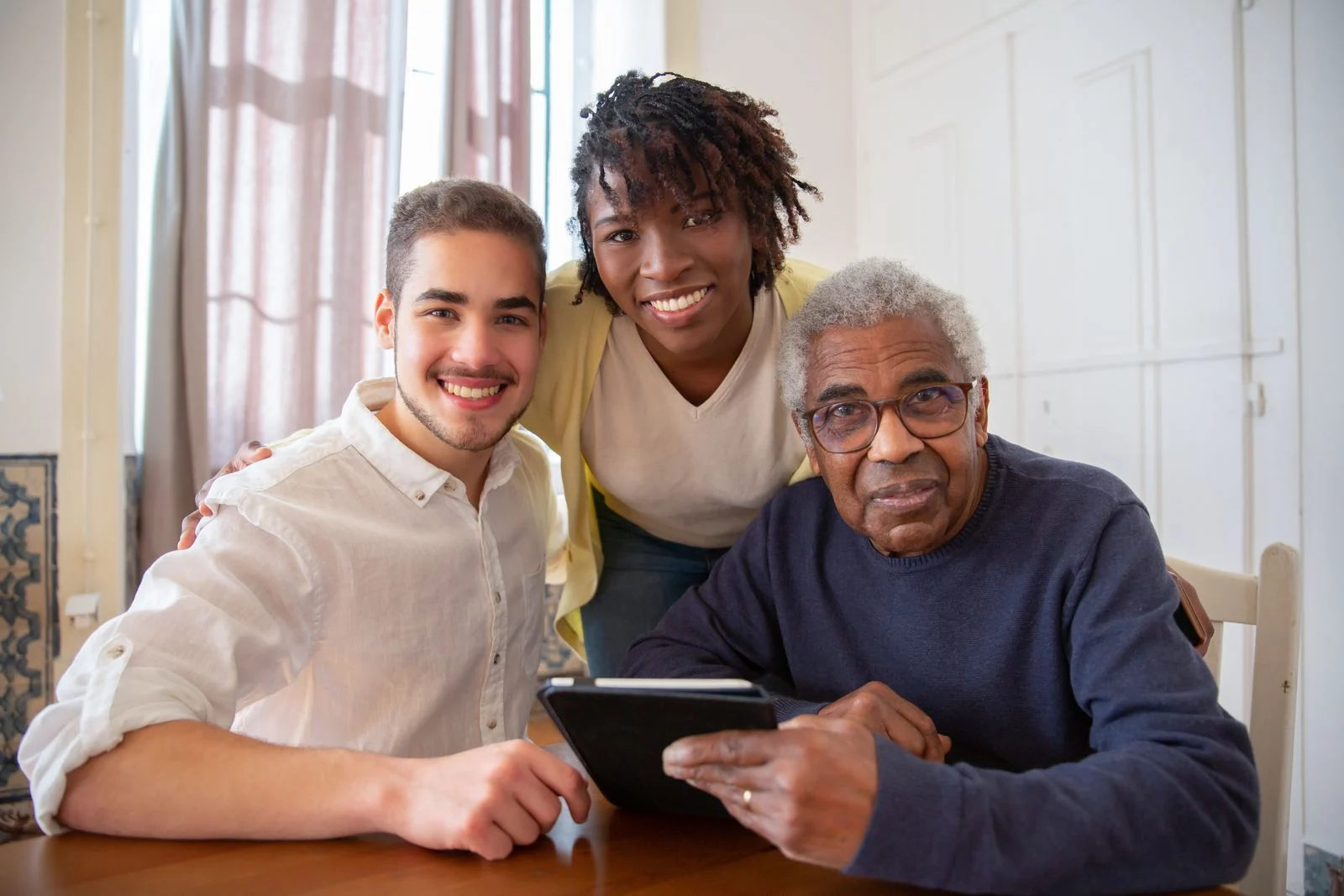 A senior smiling with two supportive caregivers at home