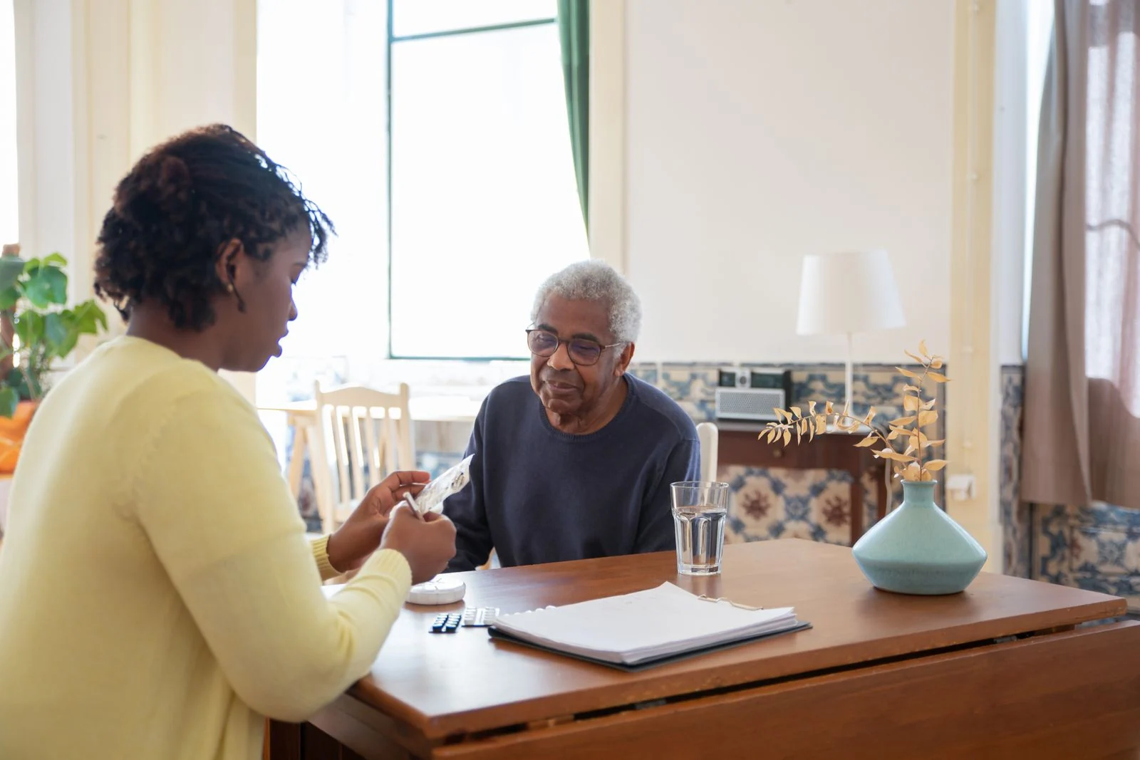 A caregiver helping a senior manage a medication routine at home