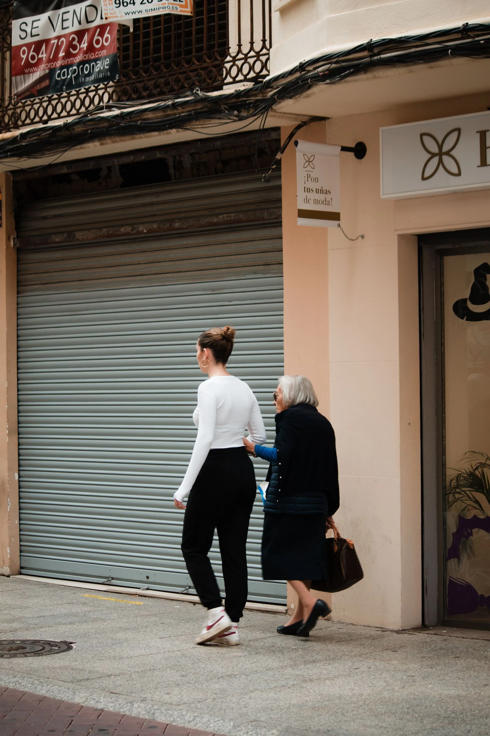 A companion helping a senior woman walk safely outdoors
